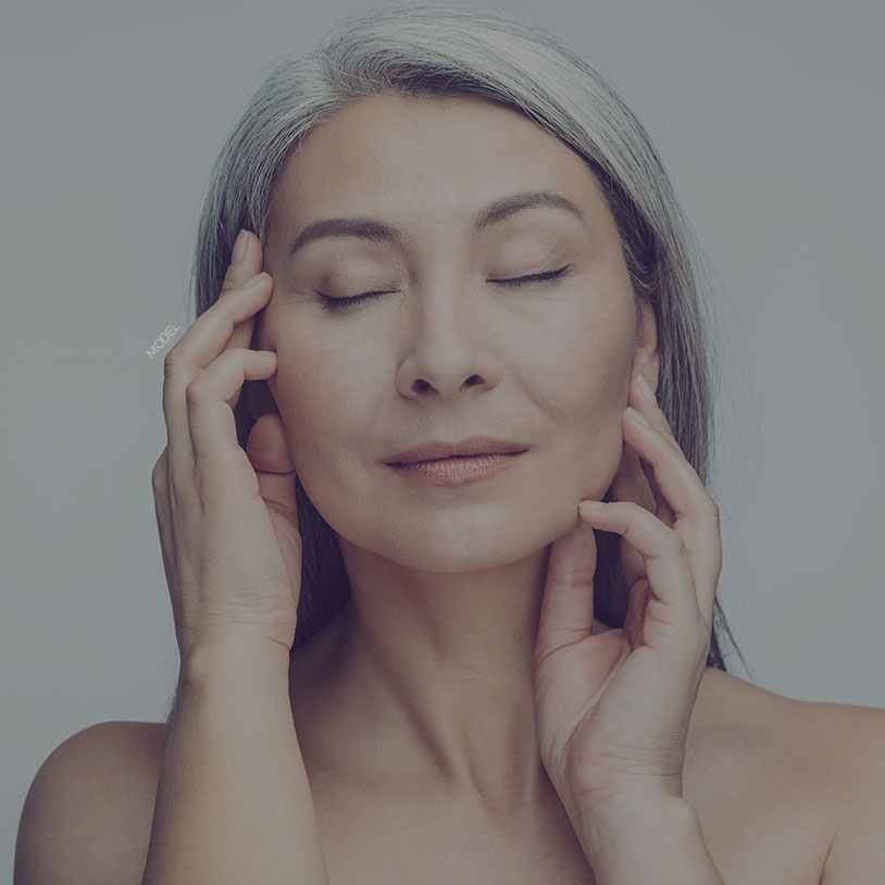 Headshot of a middle aged woman caressing her face